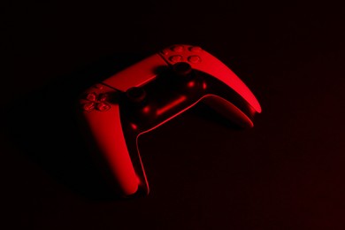 Photo of Two wireless game controllers on black background in neon light