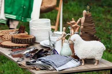 Many different decorative items on wooden table outdoors. Garage sale