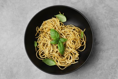 Delicious pasta with pesto sauce and basil on light grey table, top view