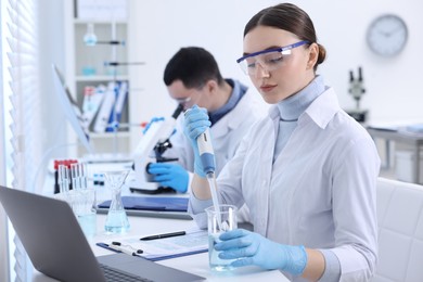 Scientist dripping sample into beaker in laboratory