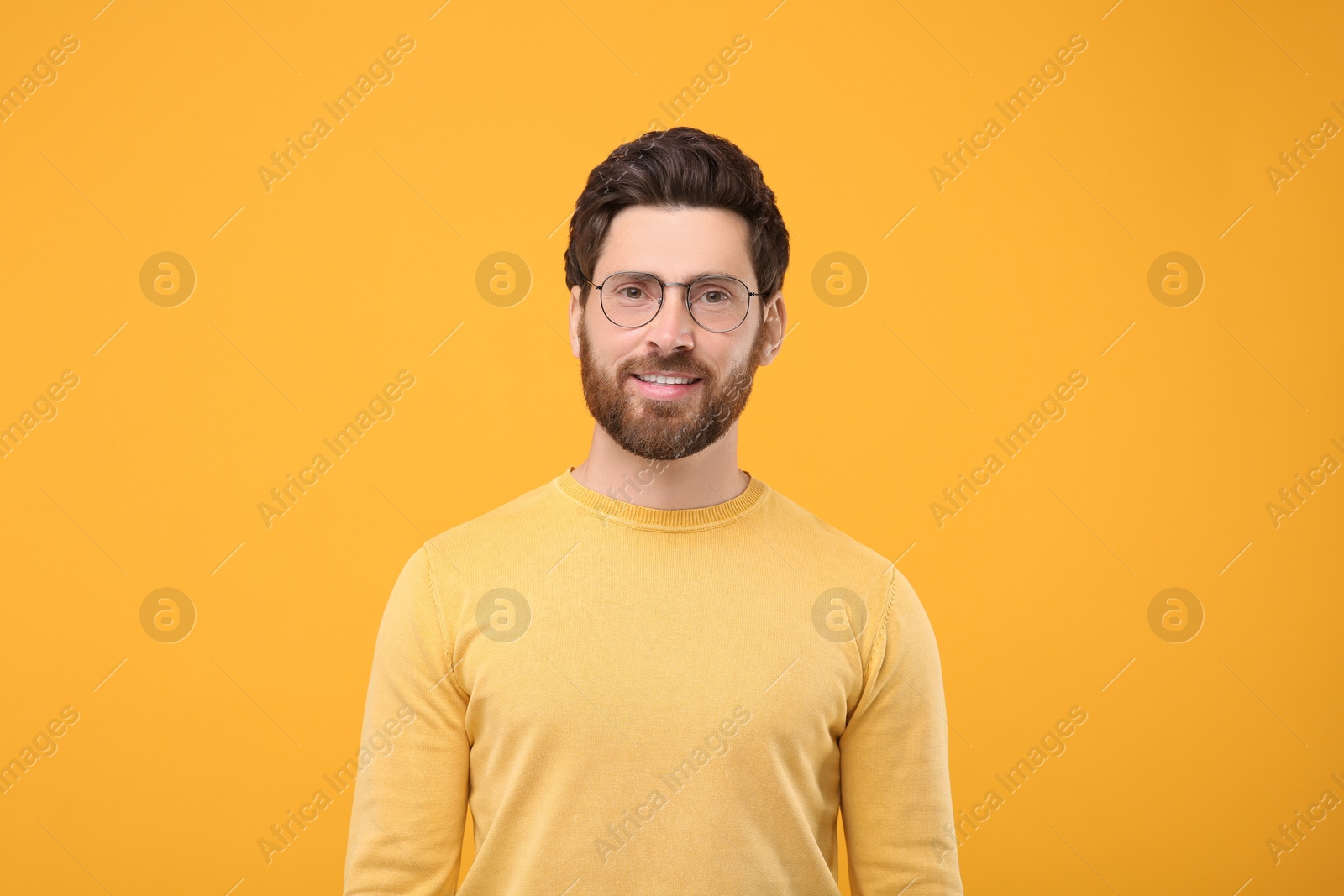 Photo of Portrait of handsome man in glasses on orange background