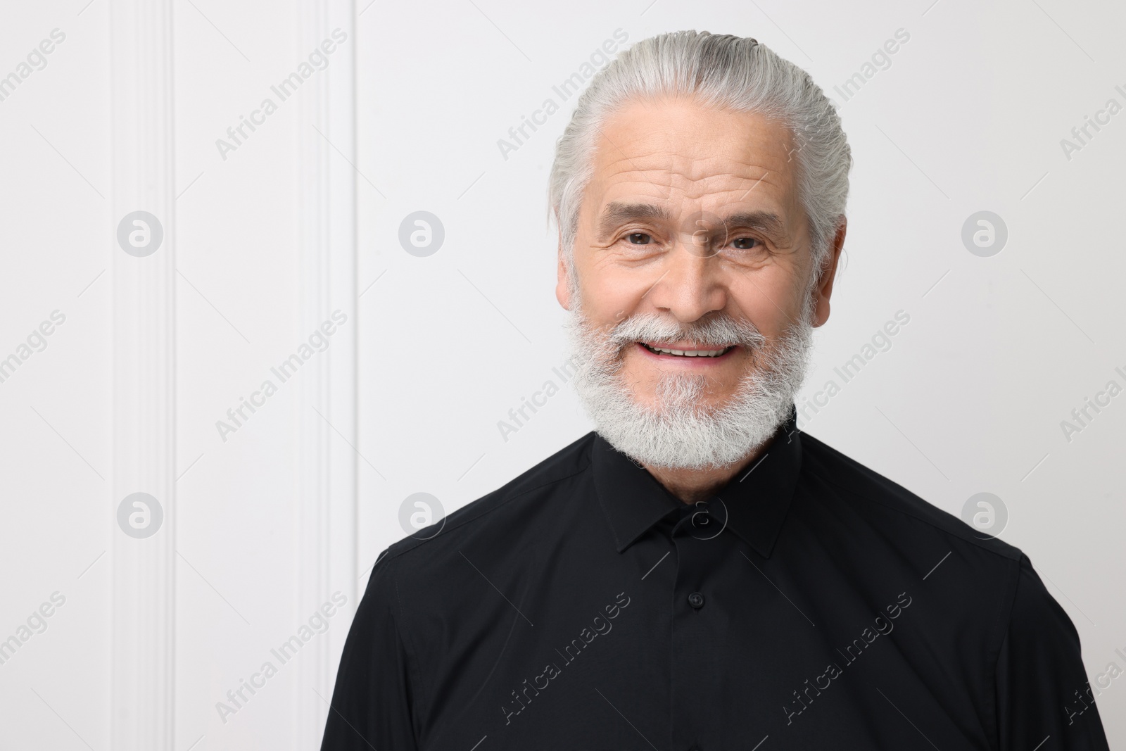 Photo of Portrait of handsome senior man near white wall. Space for text