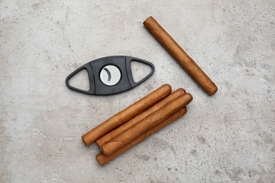 Photo of Cigars and guillotine cutter on grey table, flat lay
