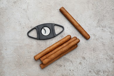 Cigars and guillotine cutter on grey table, flat lay