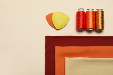 Photo of Flat lay composition with sewing threads on beige background, space for text