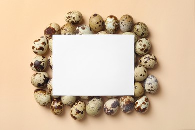 Photo of Blank card and speckled quail eggs on beige background, top view. Space for text