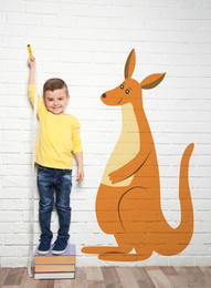 Little boy measuring height and drawing of kangaroo near white brick wall