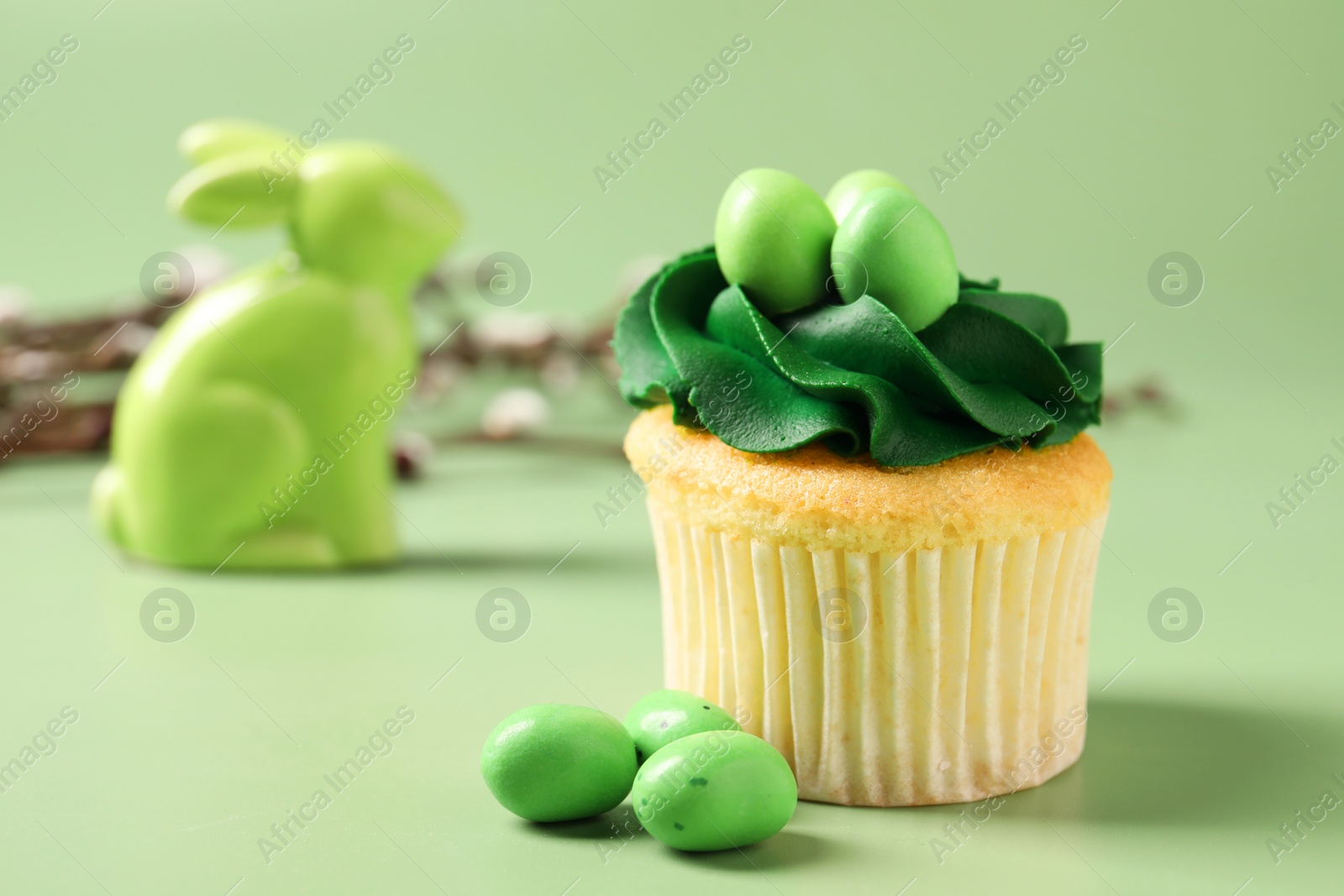 Photo of Tasty cupcake with Easter decor on green background, closeup. Space for text