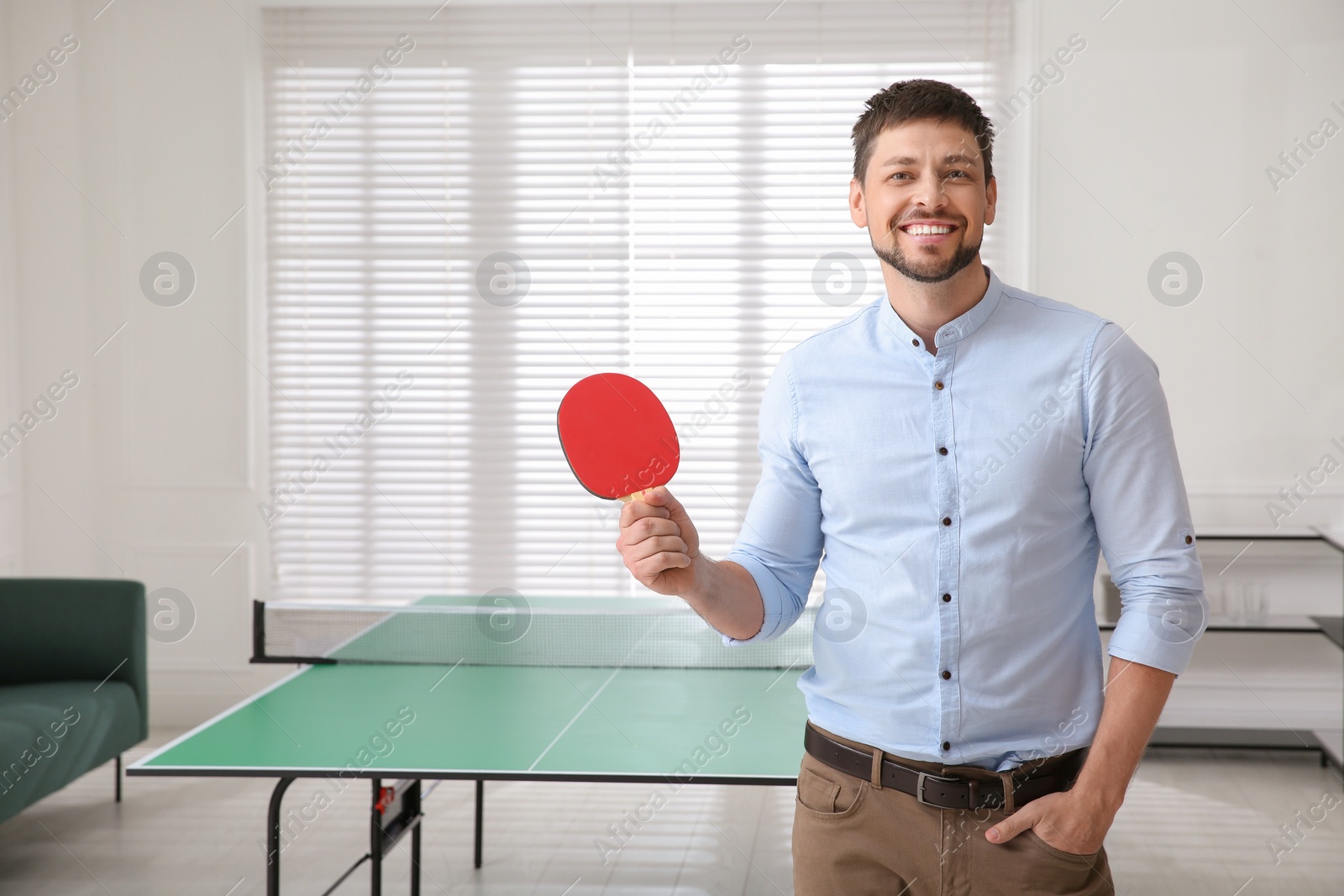 Photo of Businessman with tennis racket near ping pong table in office. Space for text