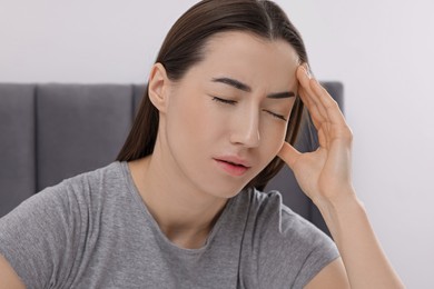 Sad woman suffering from headache at home