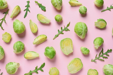 Photo of Fresh Brussels sprouts and arugula on color background, flat lay