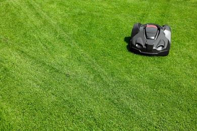 Modern robot lawn mower on green grass in garden