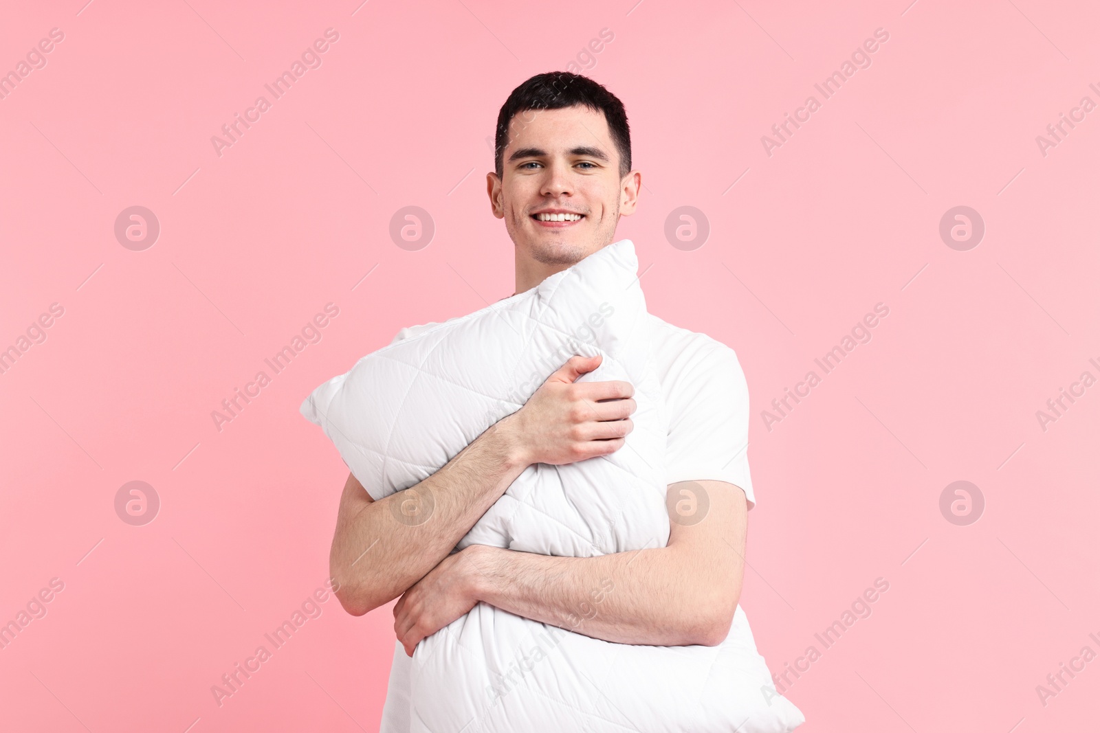 Photo of Happy man in pyjama holding pillow on pink background