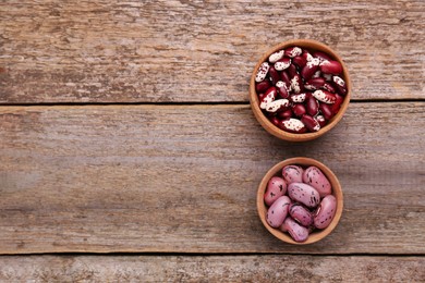 Photo of Different kinds of dry kidney beans on wooden table, flat lay. Space for text