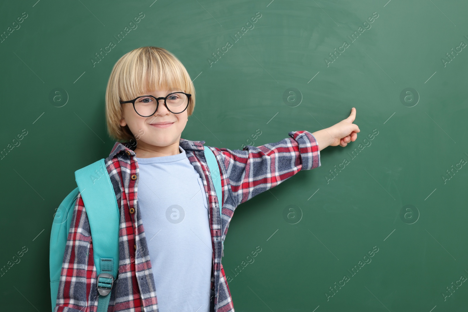 Photo of Happy little school child pointing at chalkboard