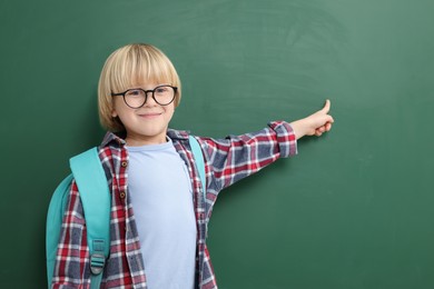 Happy little school child pointing at chalkboard