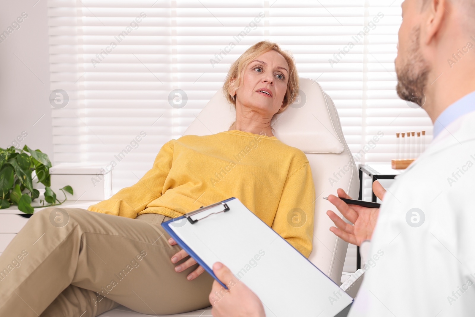 Photo of Doctor with clipboard consulting patient in clinic