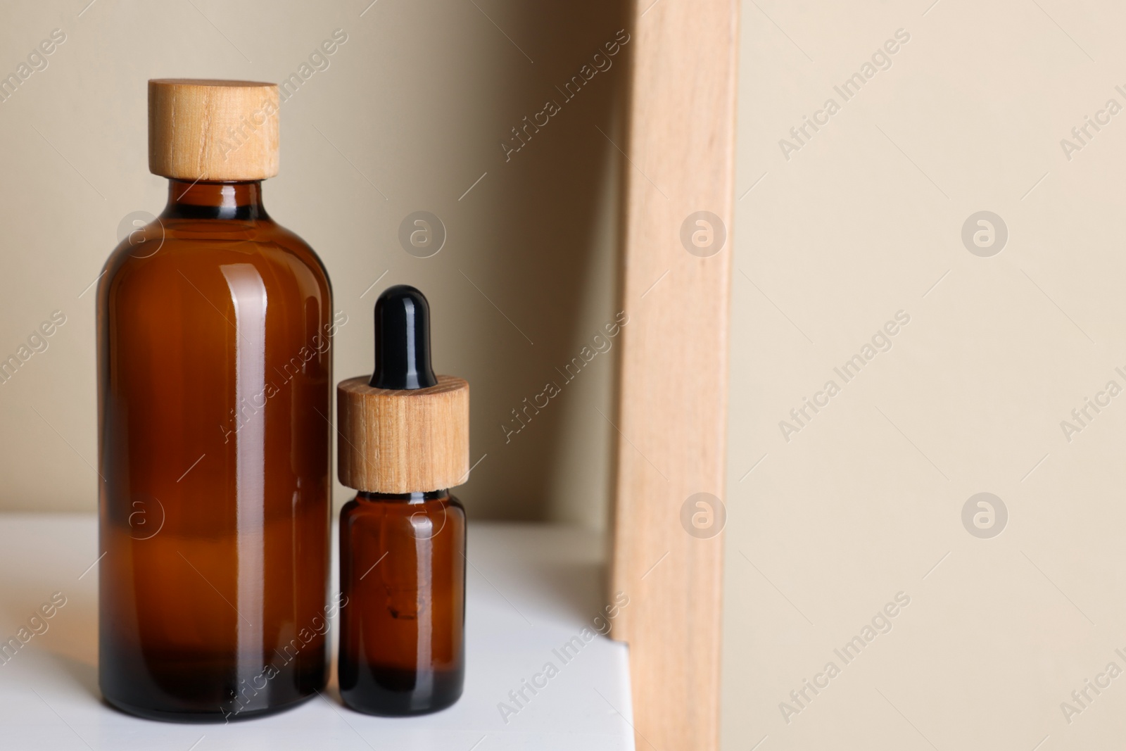 Photo of Glass bottles of cosmetic products on white shelf, space for text