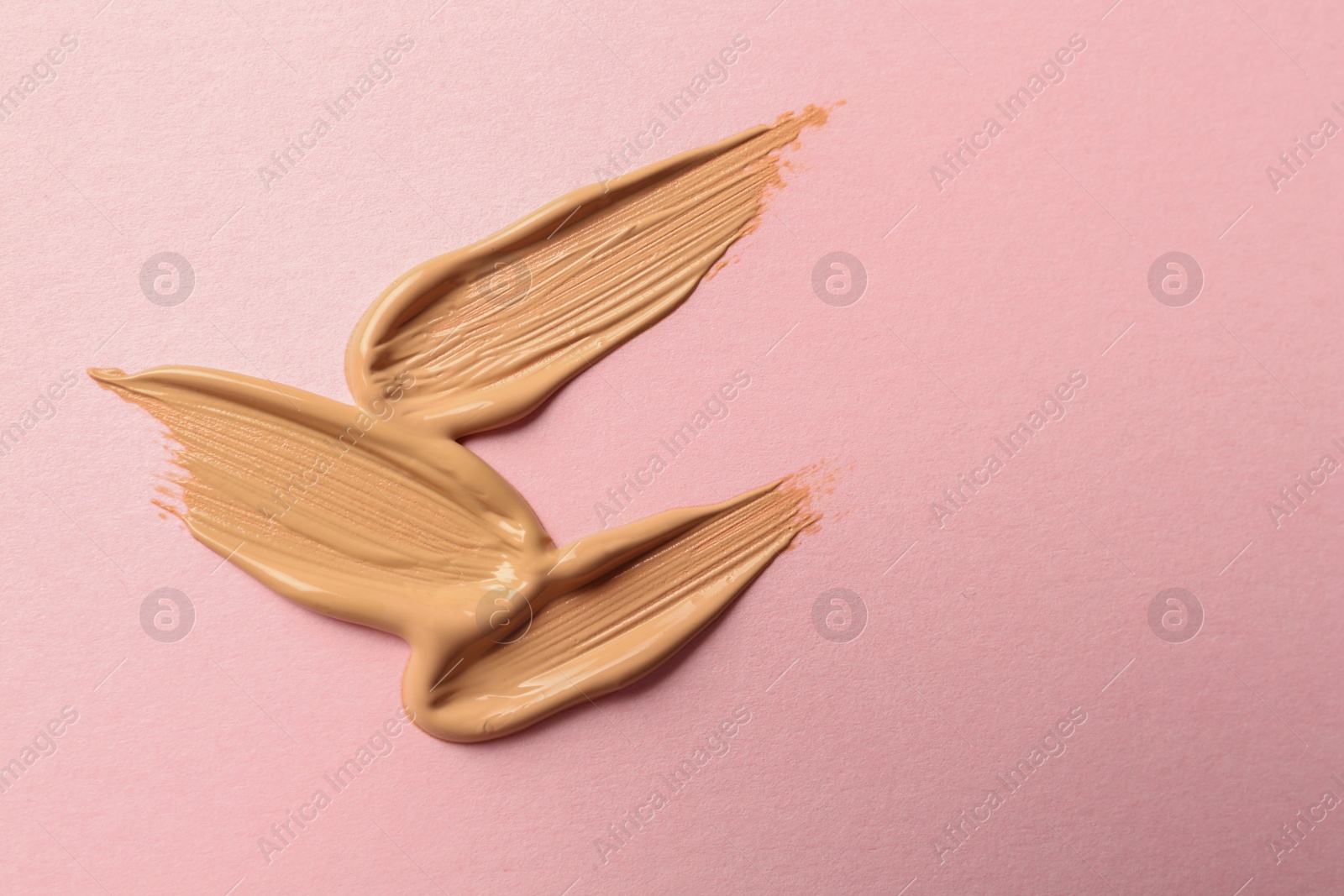 Photo of Sample of liquid skin foundation on pink background, top view. Space for text