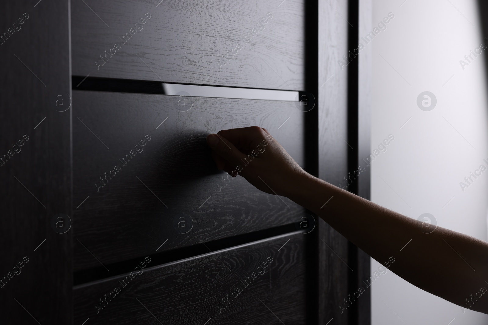 Photo of Woman knocking on door indoors, closeup view