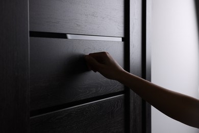 Woman knocking on door indoors, closeup view