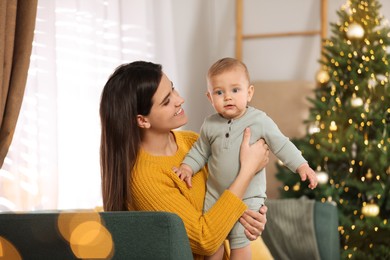 Photo of Happy young mother with her cute baby in room decorated for Christmas. Winter holiday