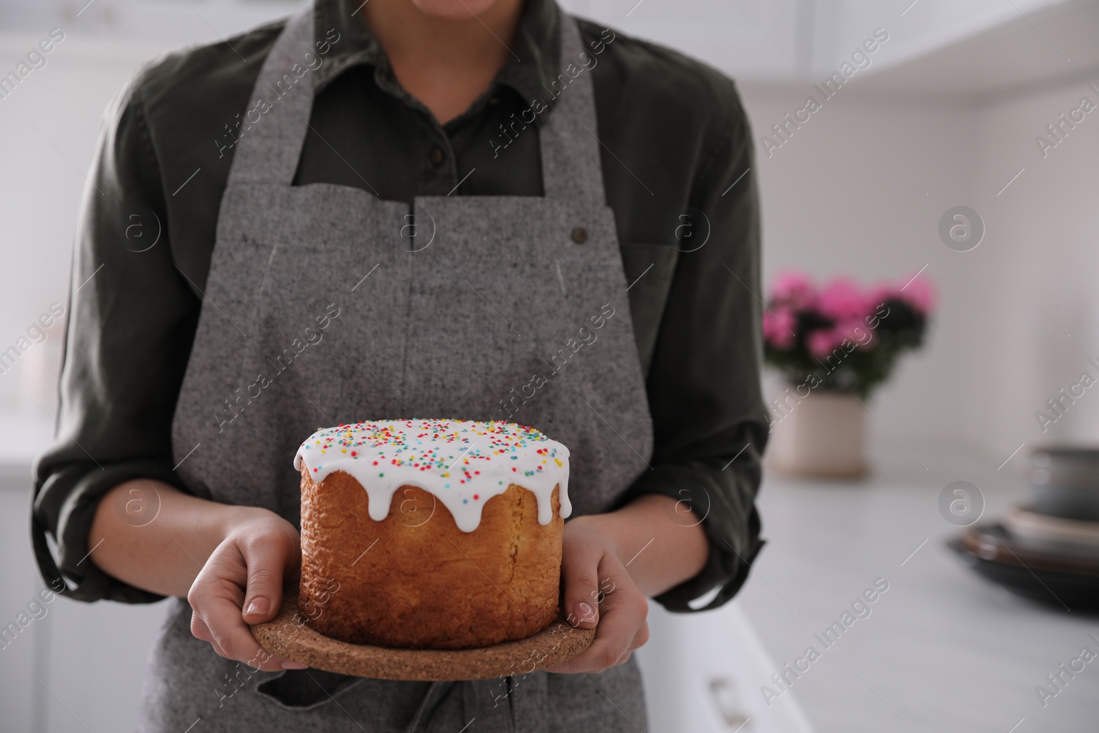 Photo of Young woman with traditional Easter cake in kitchen, closeup. Space for text