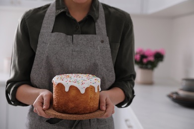 Photo of Young woman with traditional Easter cake in kitchen, closeup. Space for text