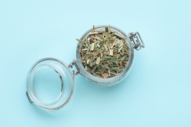 Photo of Glass jar with aromatic dried lemongrass on light blue background, top view