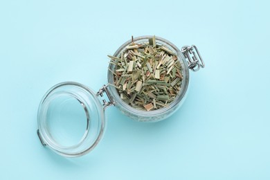 Glass jar with aromatic dried lemongrass on light blue background, top view