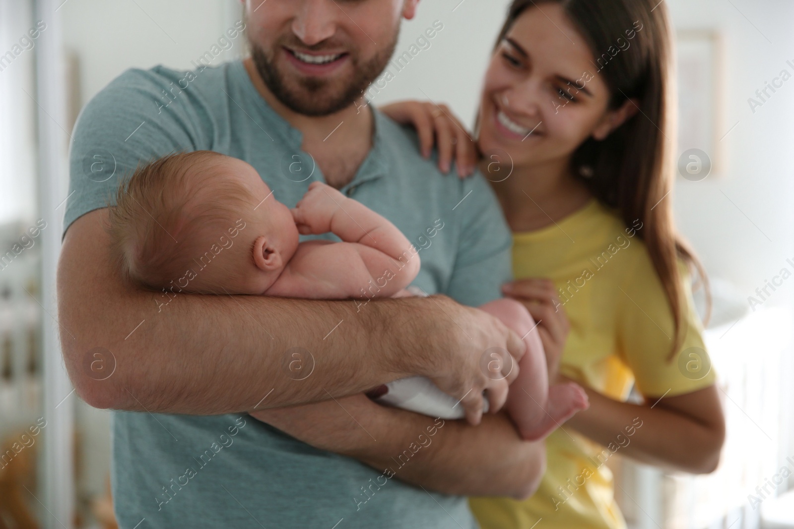 Photo of Happy couple with their newborn baby at home, closeup