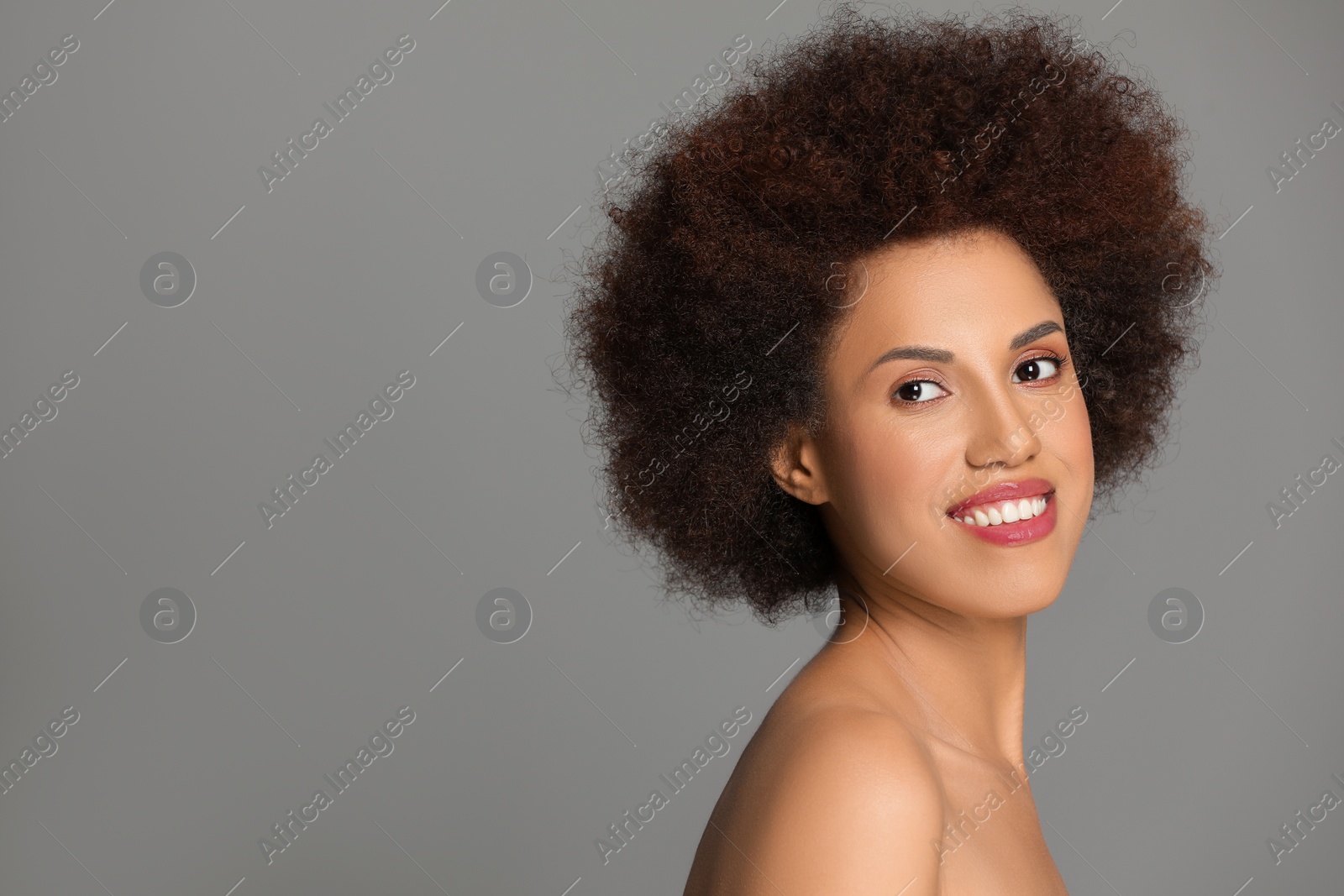 Photo of Portrait of beautiful young woman with glamorous makeup on grey background. Space for text