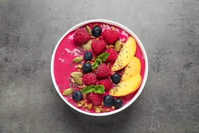 Photo of Delicious acai smoothie with granola and berries on grey table, top view