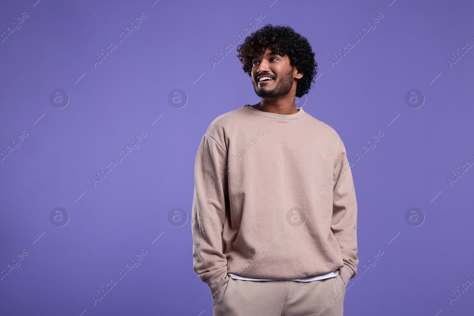 Photo of Handsome smiling man on violet background, space for text