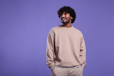 Handsome smiling man on violet background, space for text
