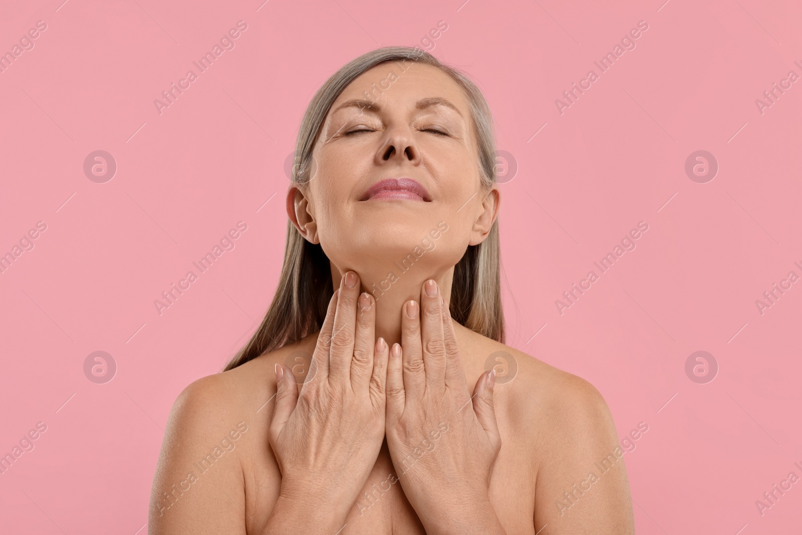 Photo of Beautiful woman touching her neck on pink background