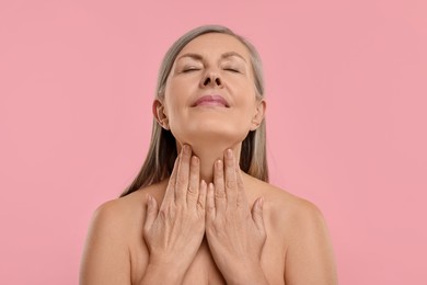 Photo of Beautiful woman touching her neck on pink background