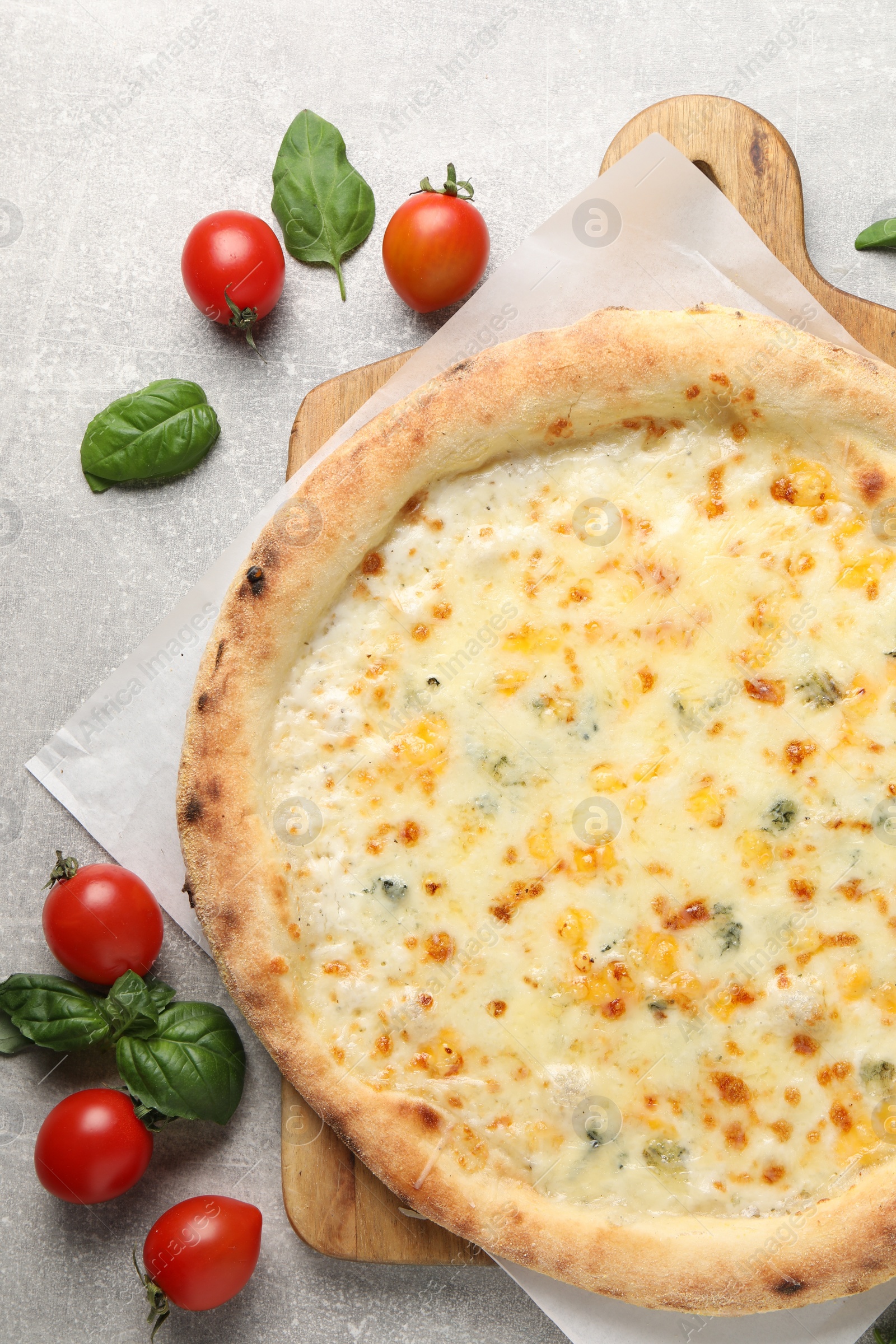 Photo of Delicious cheese pizza, basil and tomatoes on light grey table, flat lay