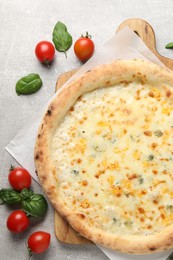 Photo of Delicious cheese pizza, basil and tomatoes on light grey table, flat lay