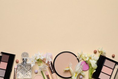 Photo of Flat lay composition with different makeup products and beautiful flowers on beige background, space for text