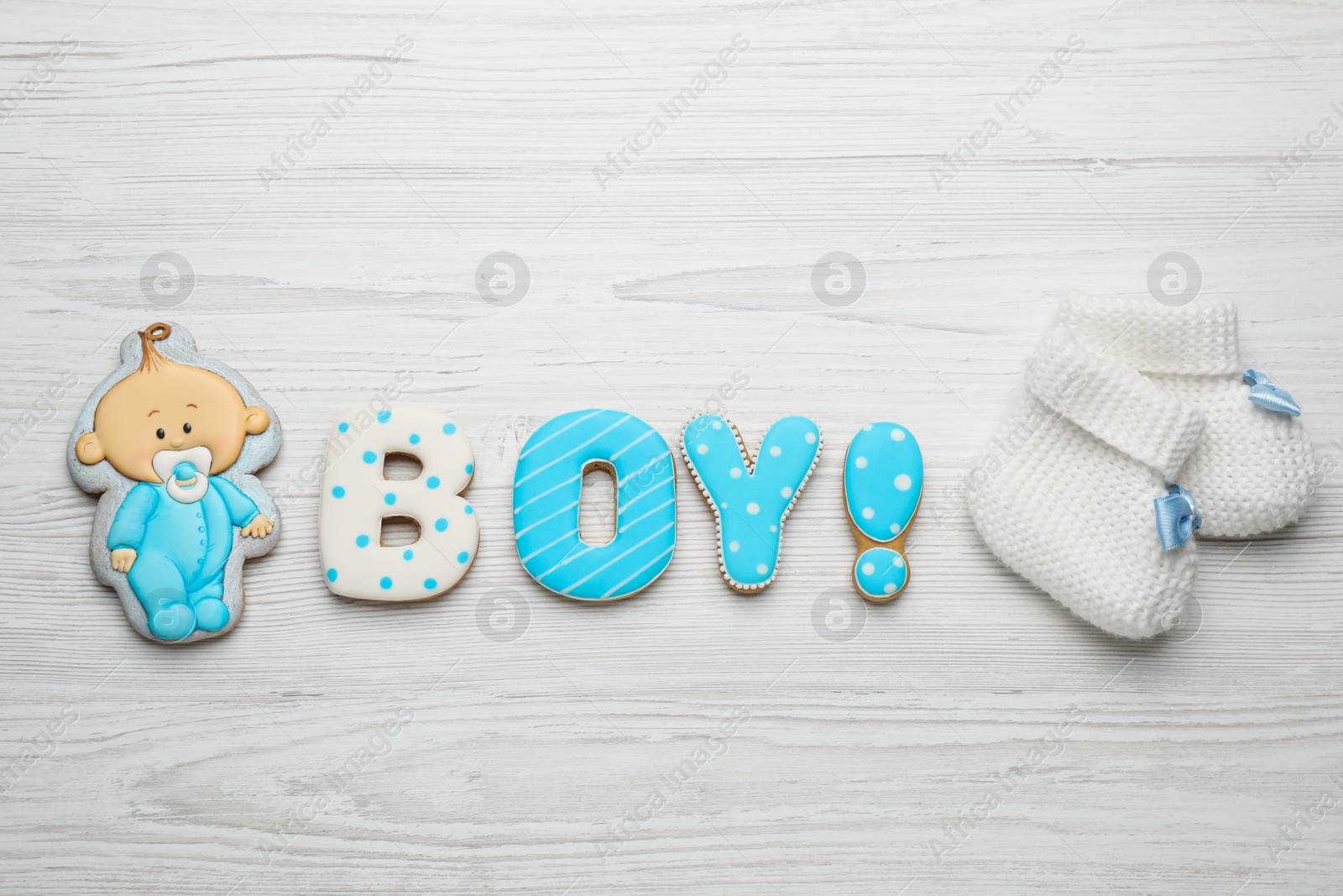 Photo of Word Boy made of tasty cookies near booties on white wooden table, flat lay. Baby shower party