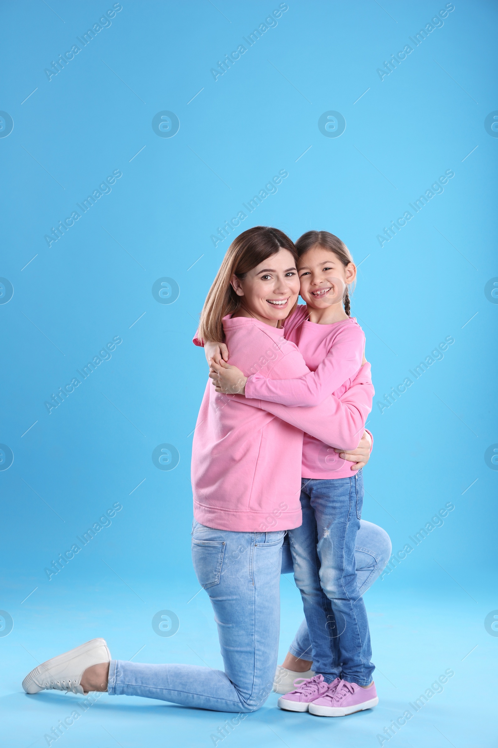 Photo of Happy woman and daughter in stylish clothes on color background