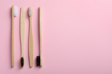 Bamboo toothbrushes on pink background, flat lay. Space for text