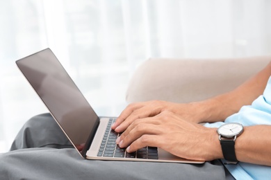 Man in casual clothes using laptop on sofa at home