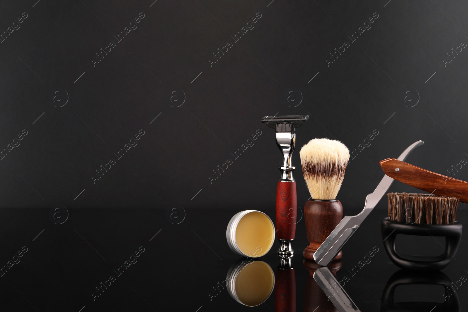 Photo of Moustache and beard styling tools on black mirror surface. Space for text