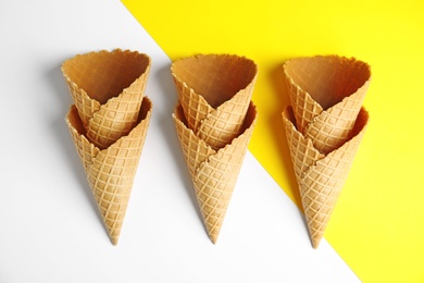 Empty wafer ice cream cones on color background, flat lay