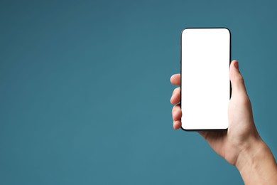 Photo of Man holding smartphone with blank screen on light blue background, closeup. Mockup for design