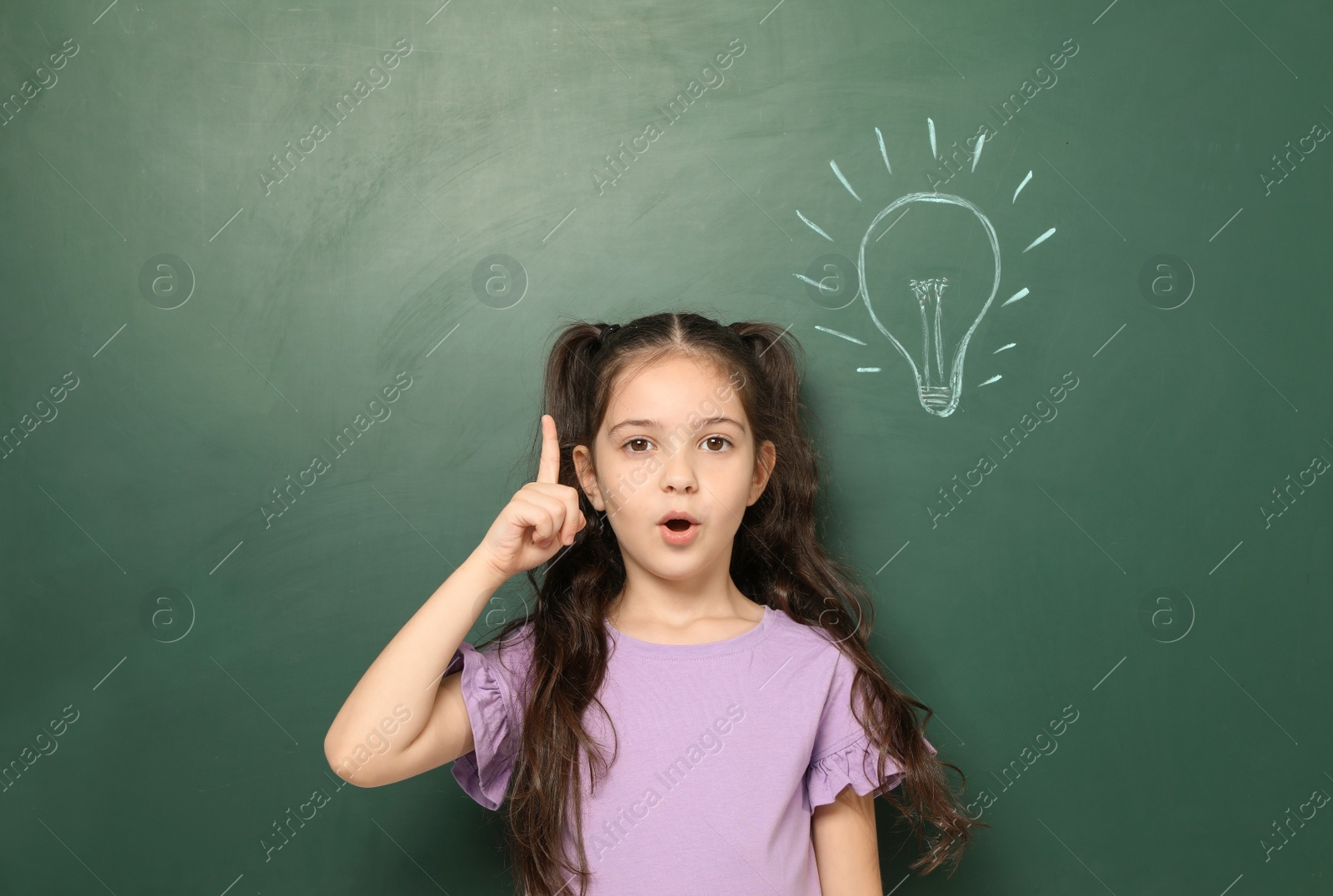 Photo of Little school child near chalkboard with lightbulb drawing