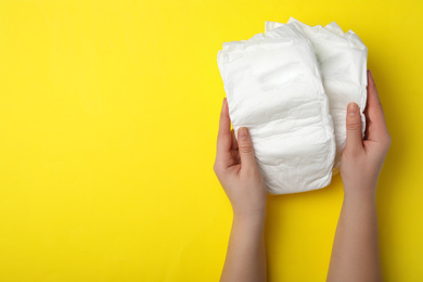 Photo of Woman with diapers on yellow background, closeup. Space for text
