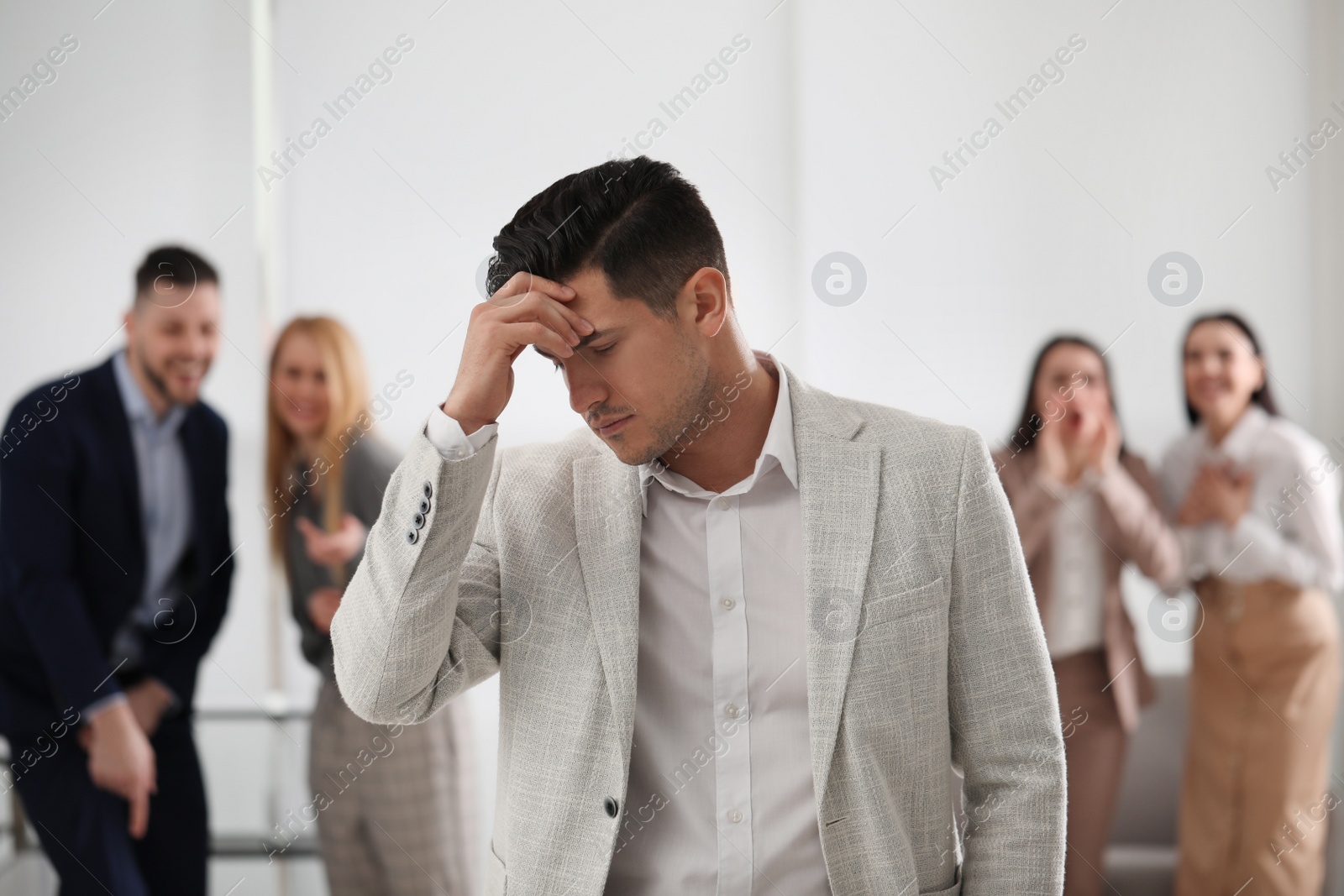 Photo of Group of coworkers bullying their colleague in office
